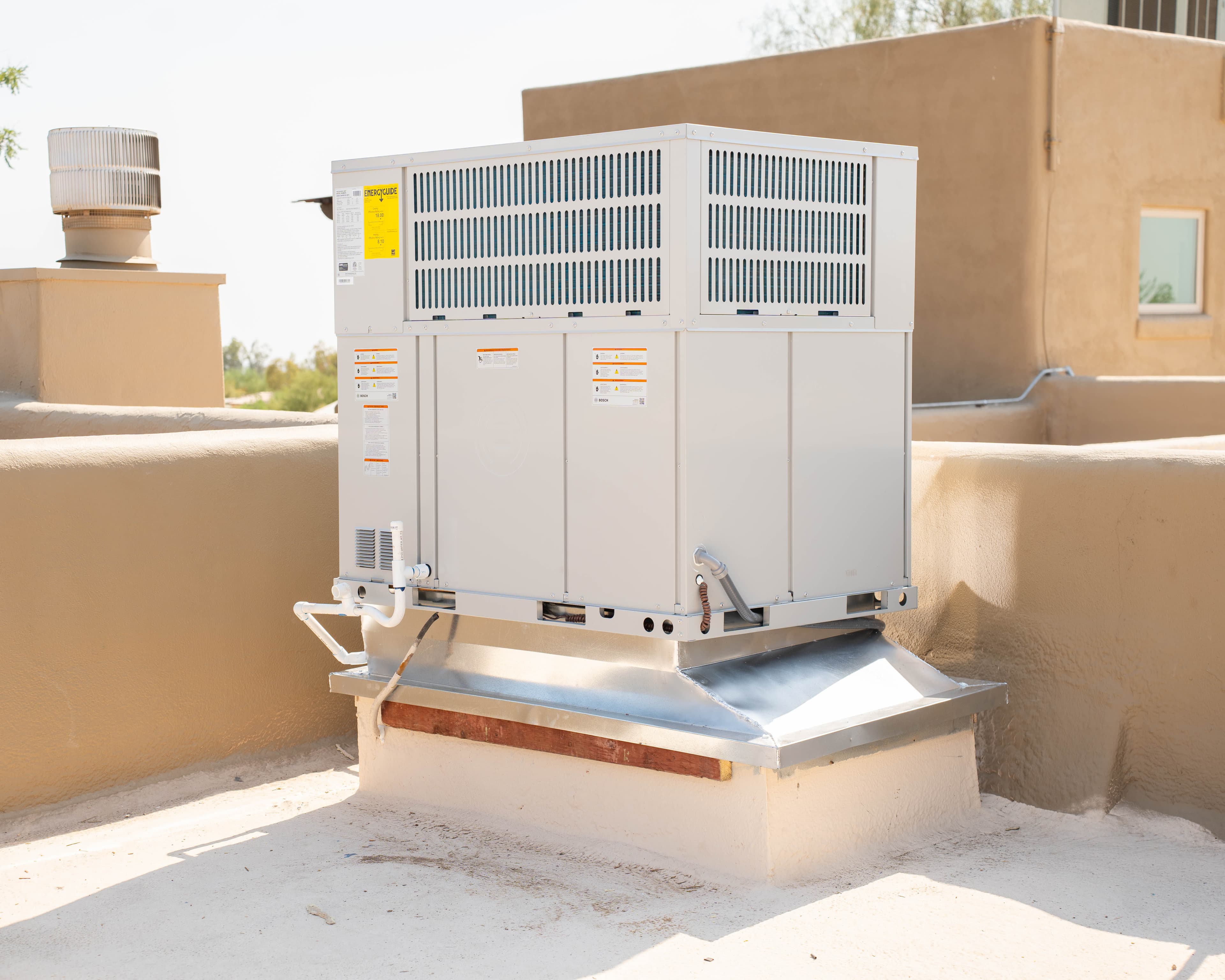 Technician inspecting a rooftop HVAC package unit on an Avondale commercial building